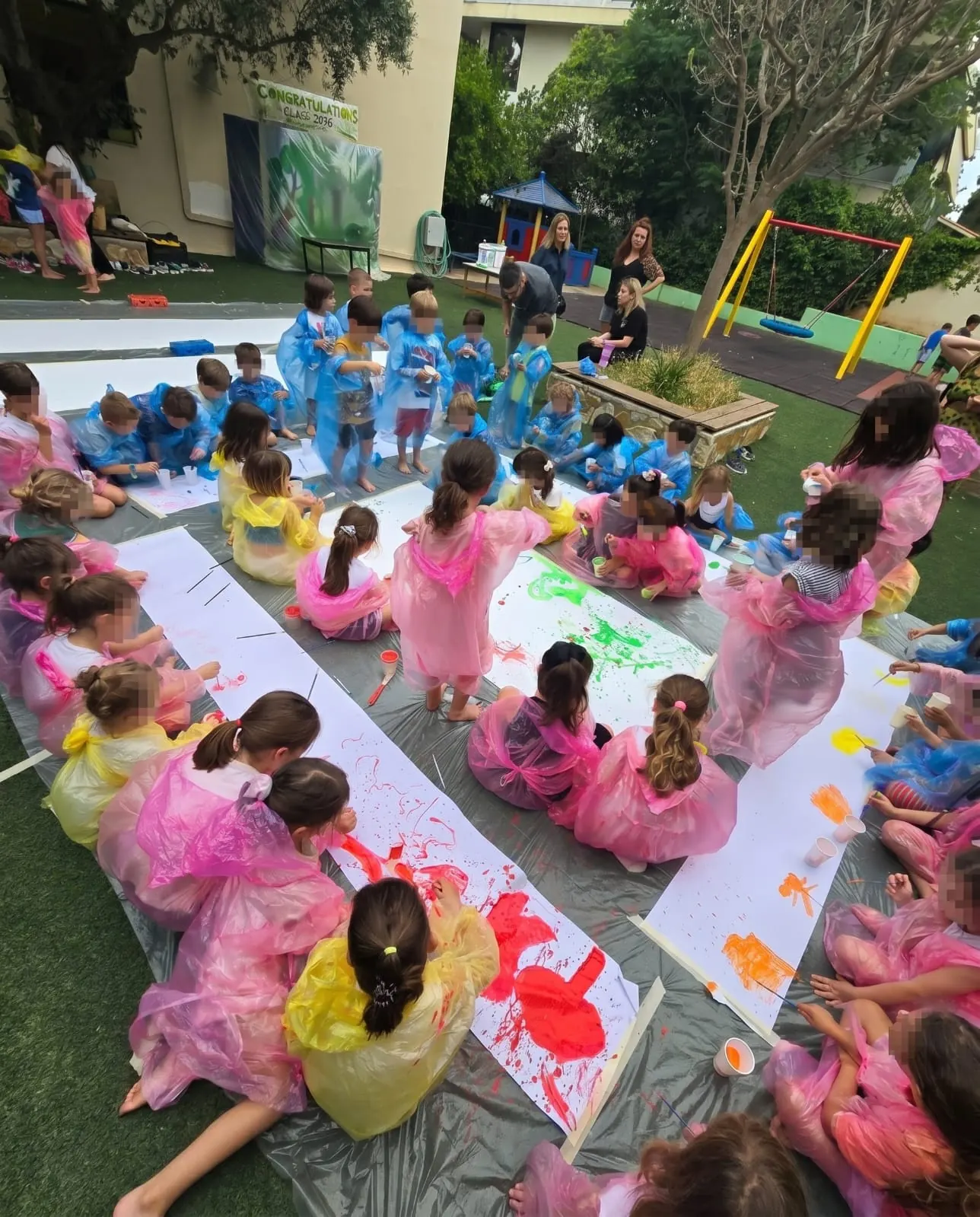 Children painting barefoot outdoors on grass during an action painting workshop